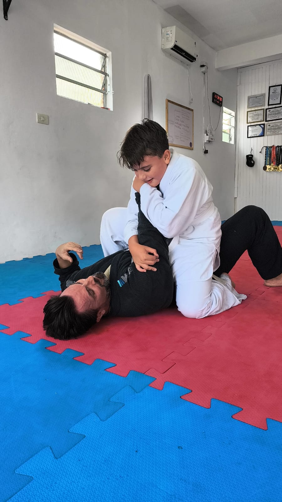 Aluno infantil praticando jiu-jitsu com o professor no tatame da Vanguard